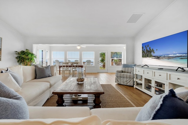 living room featuring light wood-type flooring, lofted ceiling, and crown molding