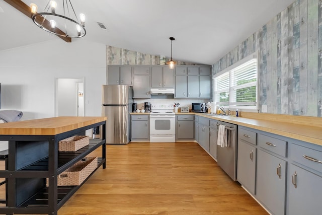 kitchen with vaulted ceiling, pendant lighting, and appliances with stainless steel finishes