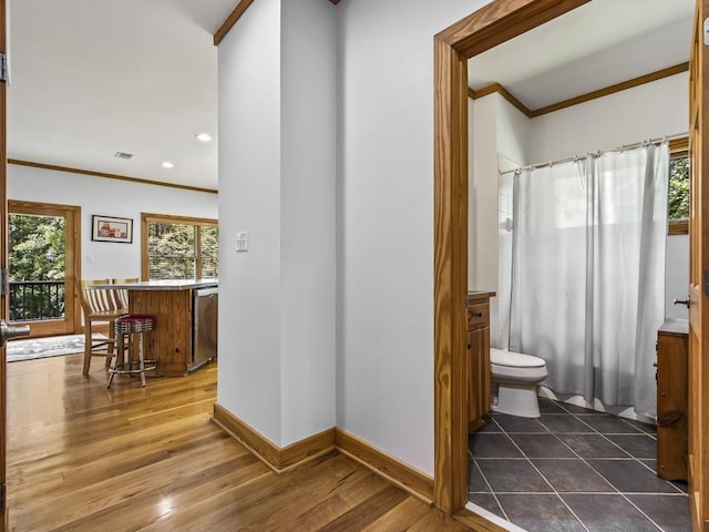 bathroom featuring hardwood / wood-style flooring, ornamental molding, toilet, and a wealth of natural light