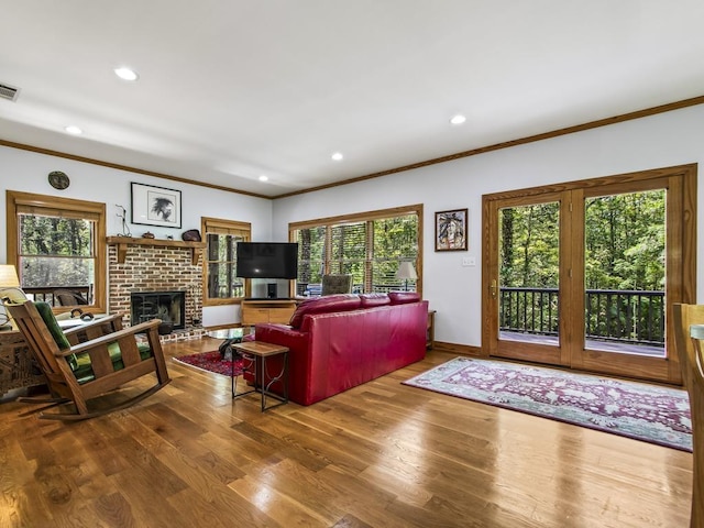 living room featuring crown molding, a brick fireplace, and hardwood / wood-style floors