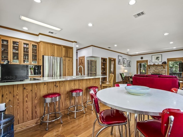 dining area featuring crown molding, light hardwood / wood-style floors, and indoor wet bar