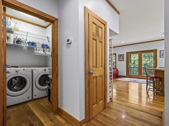 clothes washing area featuring crown molding, wood-type flooring, and washer and dryer