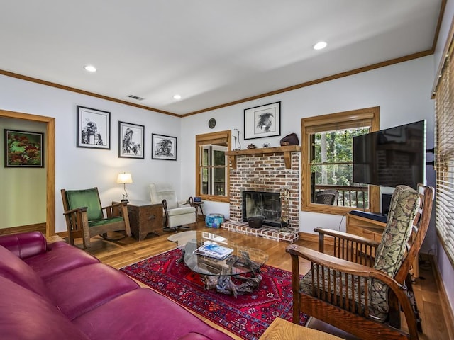 living room with ornamental molding, a brick fireplace, and hardwood / wood-style floors