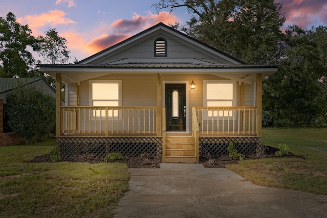 bungalow featuring covered porch and a lawn