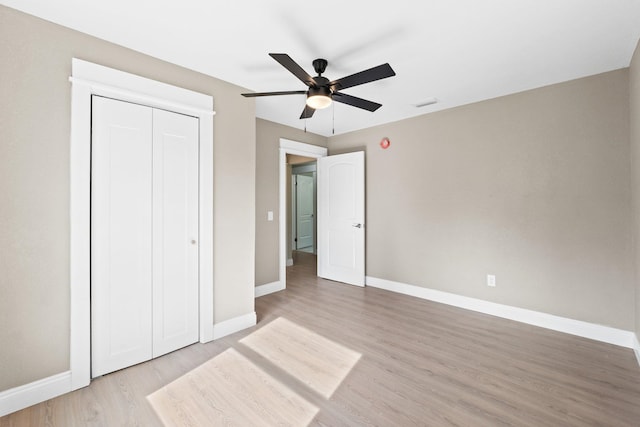 unfurnished bedroom with light wood-type flooring, ceiling fan, and a closet