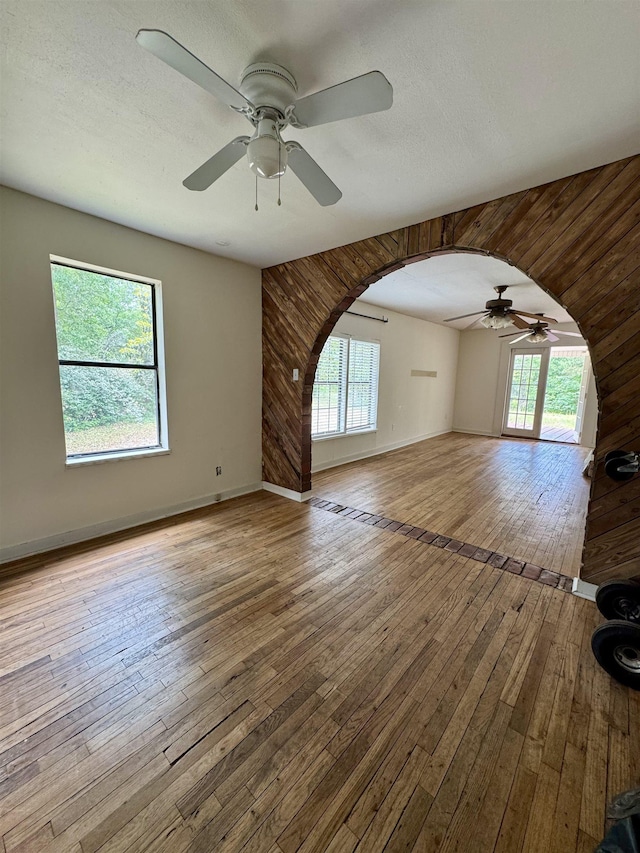 2755 Lake Bradford Rd, Tallahassee, FL 32310 - unfurnished living room with a ceiling fan, plenty of natural light, hardwood / wood-style flooring, arched walkways, and wood walls