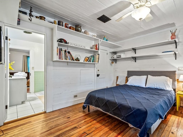 bedroom with ensuite bath, wood-type flooring, and ceiling fan