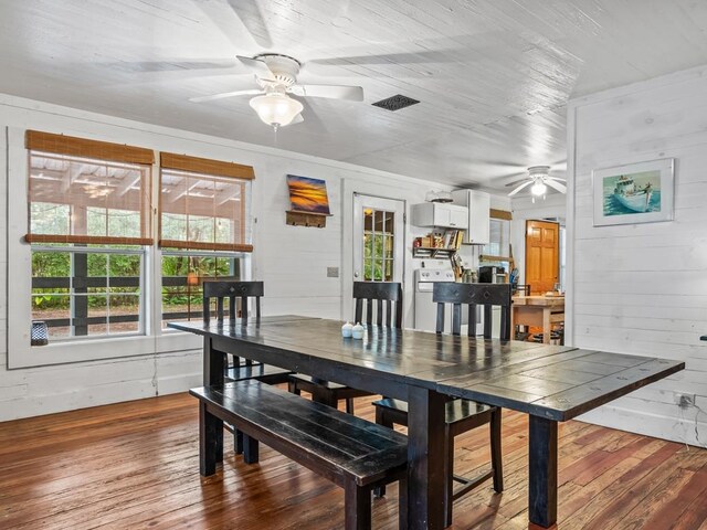 dining area featuring hardwood / wood-style flooring, a wealth of natural light, and wooden walls