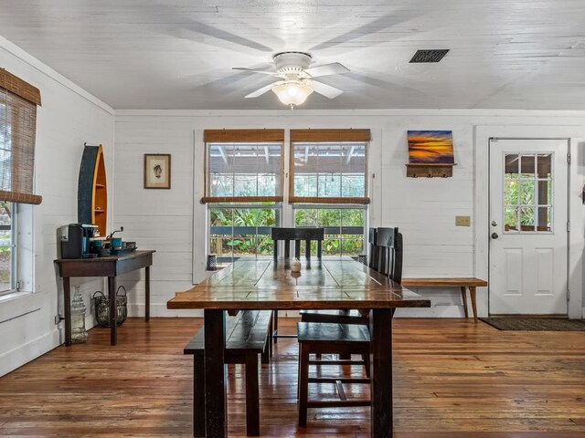 dining area featuring ceiling fan, wooden walls, hardwood / wood-style flooring, and a healthy amount of sunlight