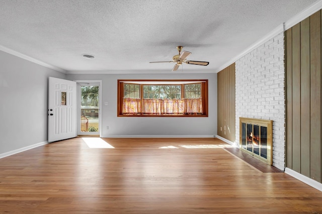 unfurnished living room featuring a brick fireplace, ornamental molding, and light hardwood / wood-style floors