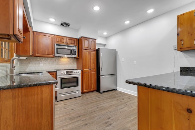 kitchen featuring sink, light hardwood / wood-style flooring, appliances with stainless steel finishes, decorative backsplash, and kitchen peninsula