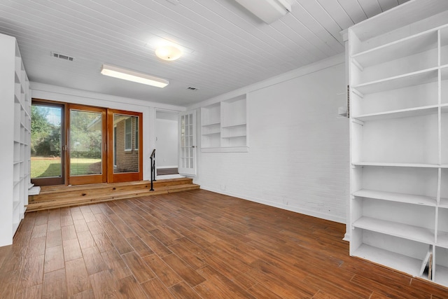 unfurnished room featuring brick wall, dark wood-type flooring, and wooden ceiling