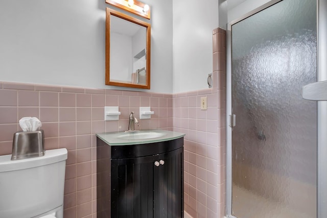 bathroom with vanity, an enclosed shower, tile walls, and toilet