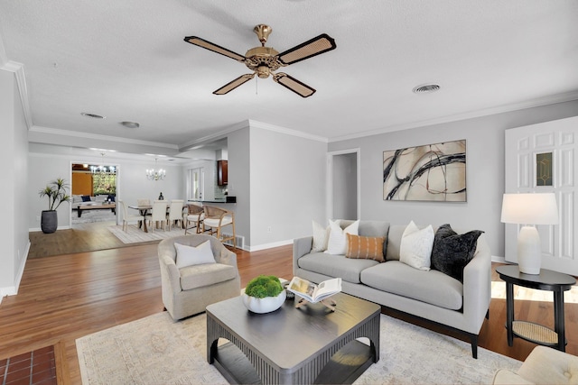 living room with crown molding, ceiling fan with notable chandelier, and light hardwood / wood-style flooring