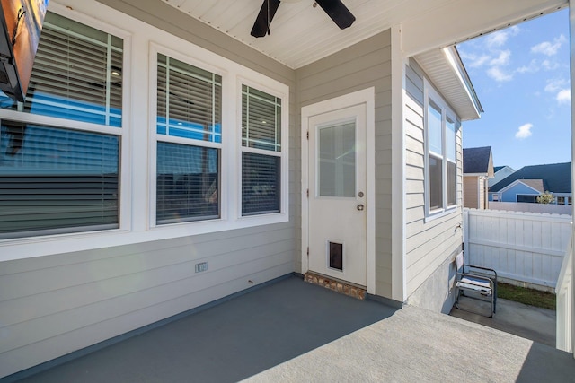 view of exterior entry with ceiling fan and a patio