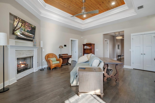 living room featuring a stone fireplace, dark hardwood / wood-style flooring, a tray ceiling, and wooden ceiling