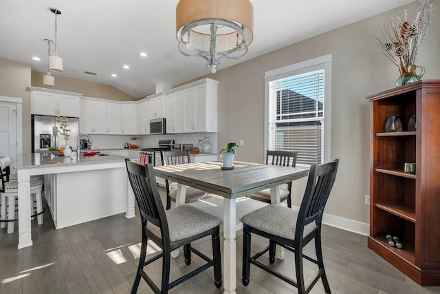 dining area with dark wood-type flooring, sink, and vaulted ceiling