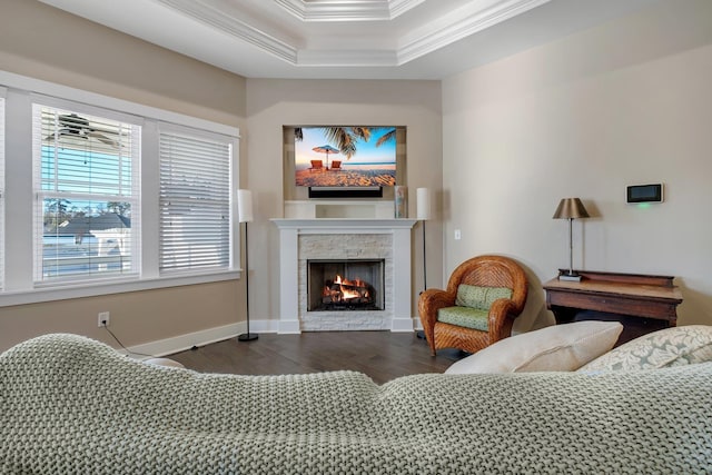 living room featuring crown molding, a stone fireplace, dark hardwood / wood-style flooring, and a tray ceiling