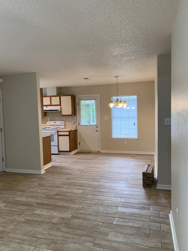 kitchen with under cabinet range hood, electric range, light wood-style floors, light countertops, and an inviting chandelier