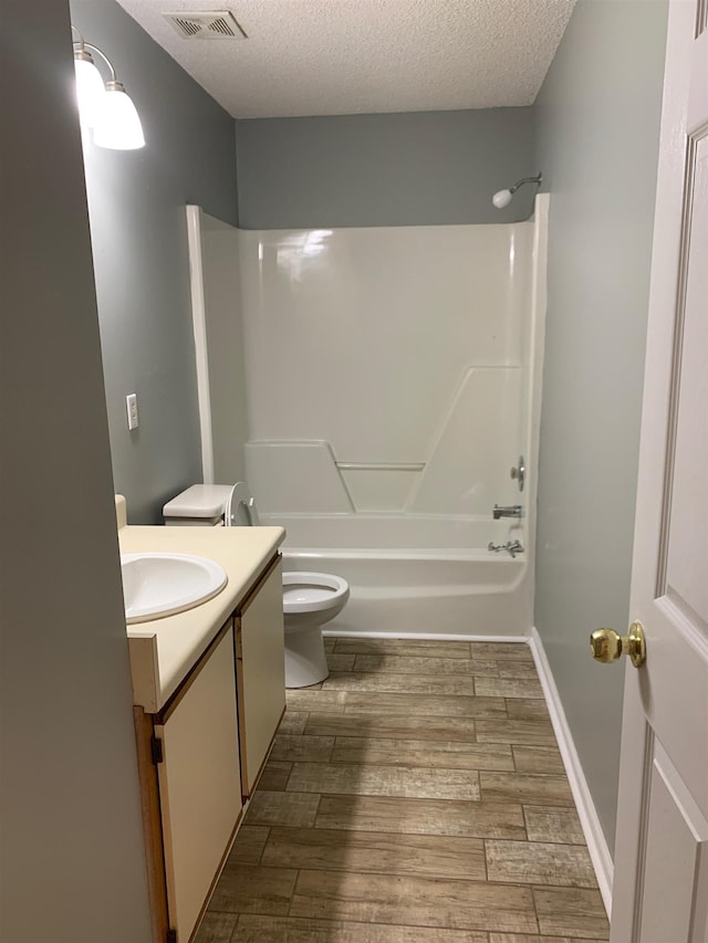 bathroom with visible vents, toilet, a textured ceiling, vanity, and wood finish floors