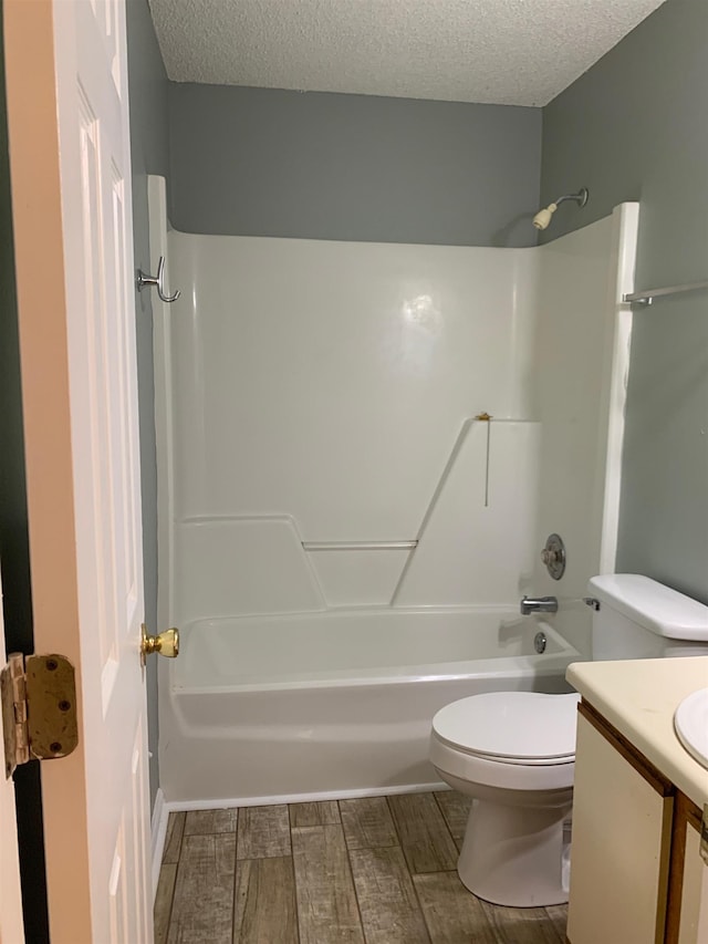 bathroom with a textured ceiling, toilet, wood finish floors, shower / bath combination, and vanity