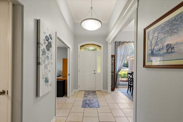 entryway with light tile patterned floors and crown molding