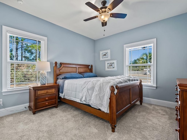 carpeted bedroom featuring multiple windows and ceiling fan