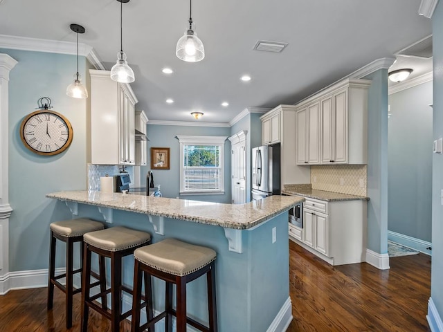 kitchen featuring pendant lighting, white cabinetry, stainless steel appliances, and crown molding