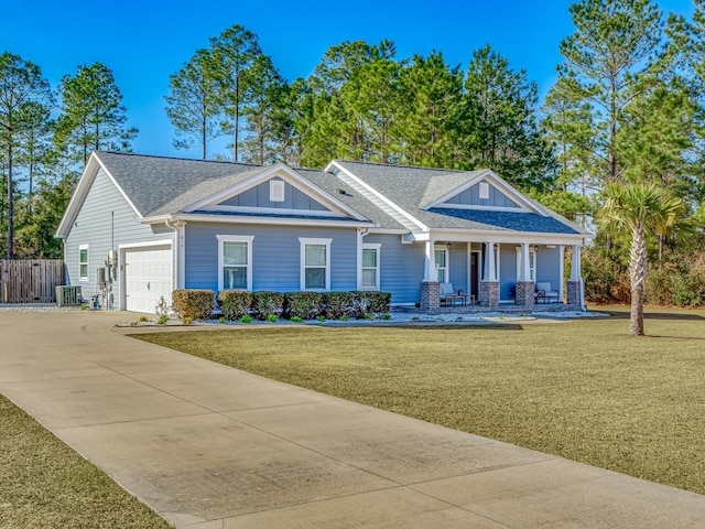 view of front of property featuring a garage, central AC, a front yard, and covered porch