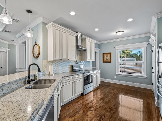 kitchen with pendant lighting, sink, stainless steel appliances, light stone countertops, and wall chimney range hood