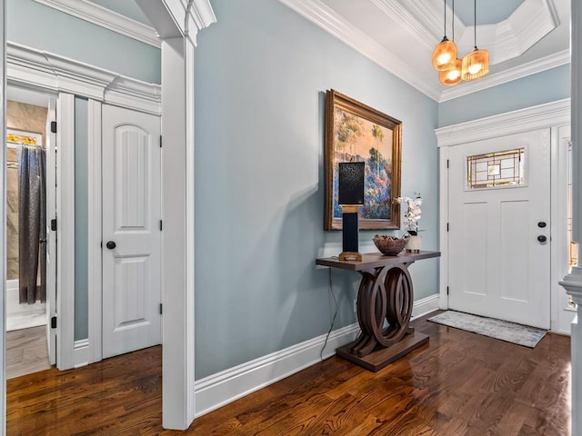 entrance foyer featuring dark wood-type flooring, ornamental molding, a raised ceiling, and a chandelier