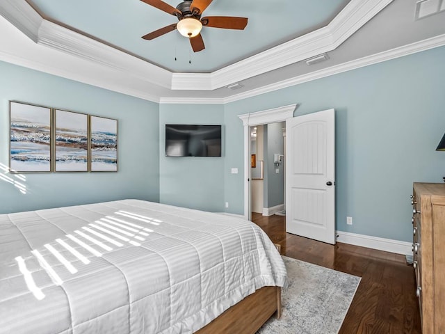 bedroom with dark wood-type flooring, ornamental molding, a raised ceiling, and ceiling fan