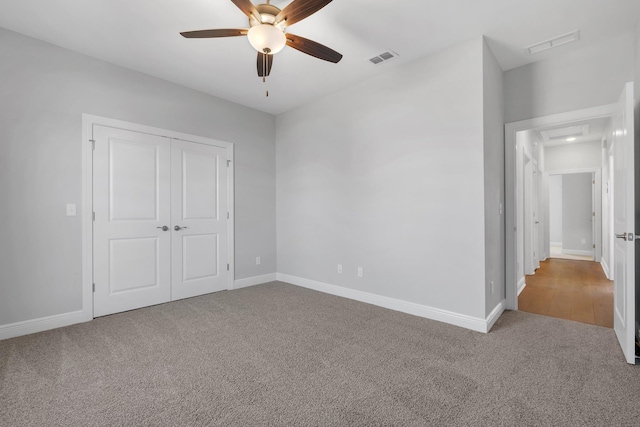 unfurnished bedroom featuring ceiling fan, a closet, and light carpet