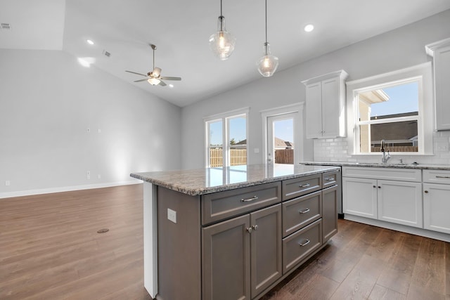 kitchen featuring lofted ceiling, sink, tasteful backsplash, pendant lighting, and white cabinets