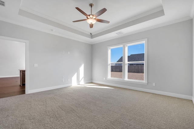 carpeted empty room featuring a tray ceiling, ornamental molding, and ceiling fan