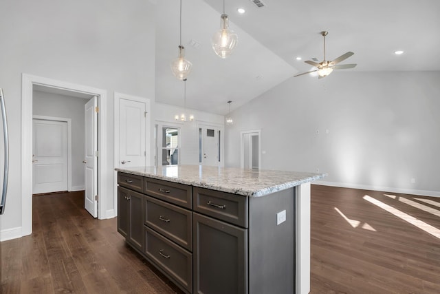 kitchen with a center island, dark hardwood / wood-style flooring, pendant lighting, ceiling fan, and light stone countertops