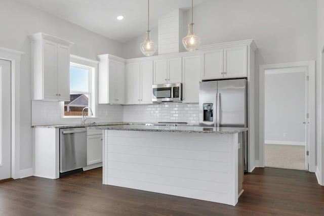 kitchen featuring light stone counters, a center island, white cabinets, and appliances with stainless steel finishes