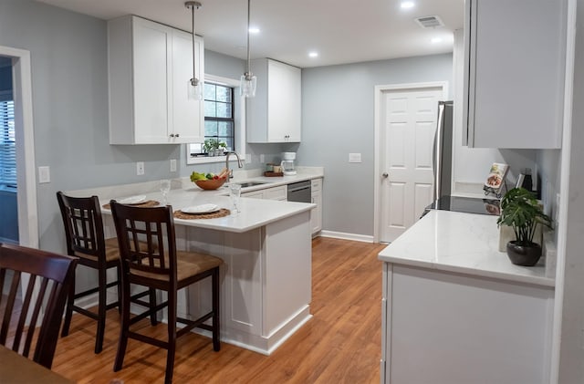 kitchen with a breakfast bar area, visible vents, white cabinetry, light wood-type flooring, and a peninsula