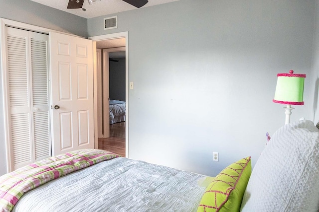 unfurnished bedroom with a closet, wood finished floors, visible vents, and a ceiling fan