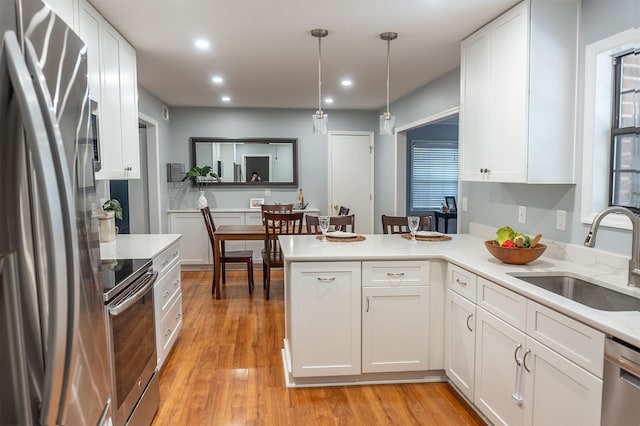 kitchen with appliances with stainless steel finishes, light countertops, a sink, and a peninsula