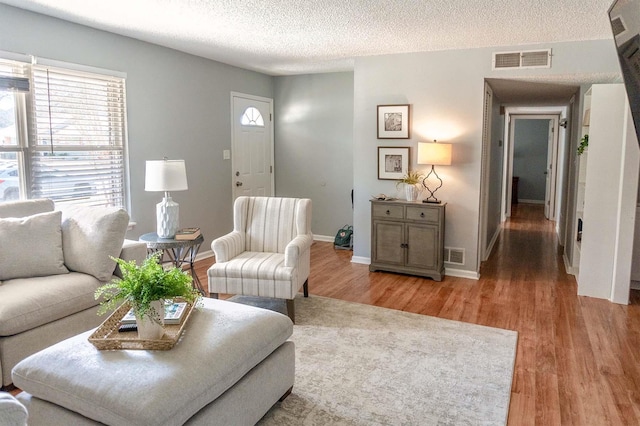 living area featuring light wood-style floors, a wealth of natural light, and visible vents