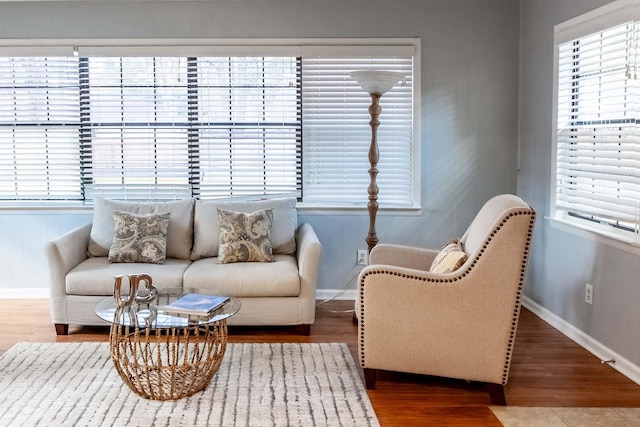 sitting room with baseboards, wood finished floors, and a healthy amount of sunlight