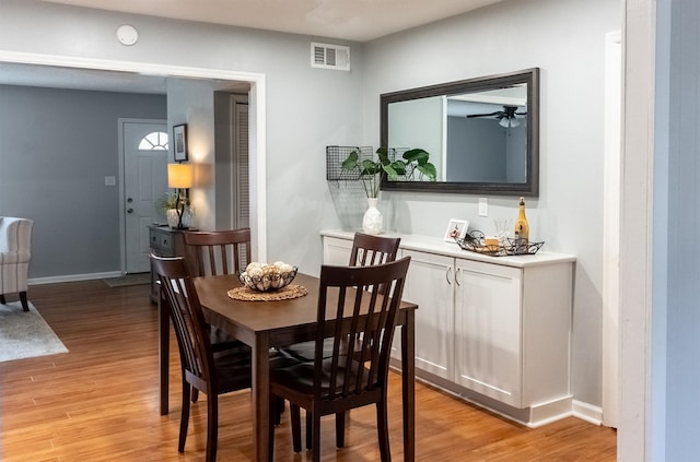 dining area with light wood-type flooring, visible vents, and baseboards