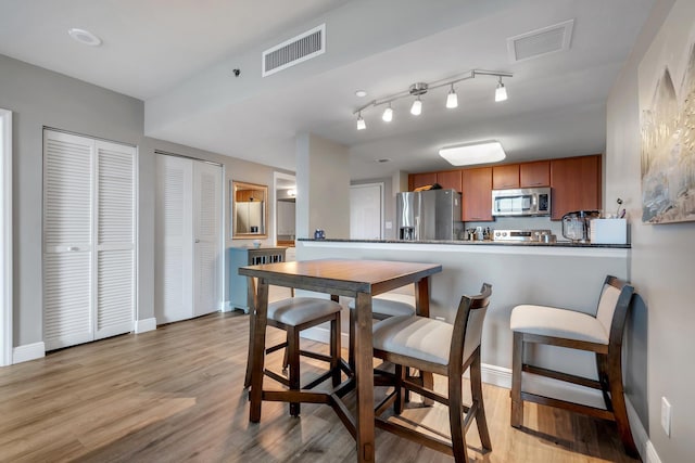 300 S Duval St # 1408, Tallahassee, FL 32301 - kitchen featuring appliances with stainless steel finishes, brown cabinets, light wood-style floors, dark countertops, and baseboards