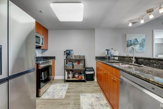 300 S Duval St # 1408, Tallahassee, FL 32301 - kitchen with appliances with stainless steel finishes, a sink, light wood-style flooring, dark stone countertops, and brown cabinets