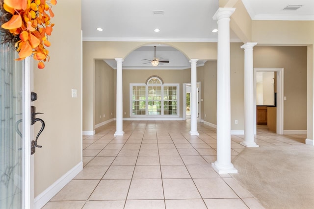 carpeted foyer featuring ceiling fan, crown molding, and decorative columns