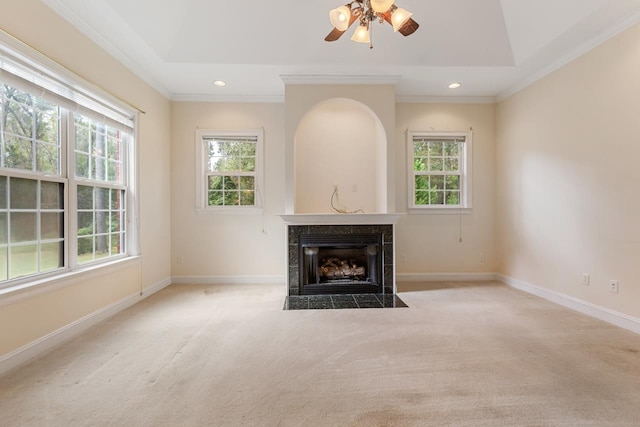 unfurnished living room with ceiling fan, a tile fireplace, light carpet, and ornamental molding