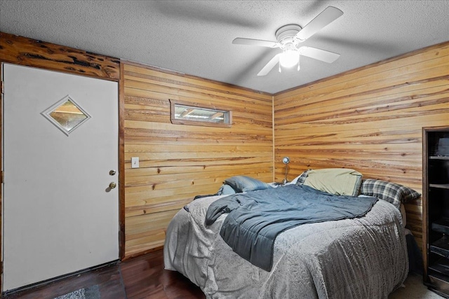 2056 N Sam Poppell Rd, Perry, FL 32347 - bedroom with wood walls, a textured ceiling, wood finished floors, and a ceiling fan