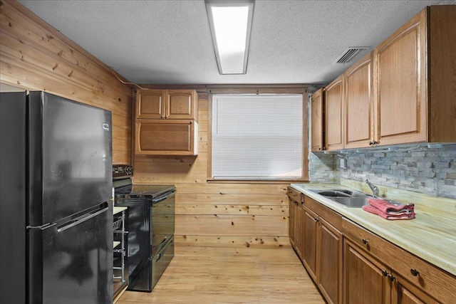 2056 N Sam Poppell Rd, Perry, FL 32347 - kitchen featuring black appliances, wood walls, light countertops, a textured ceiling, and light wood-style floors