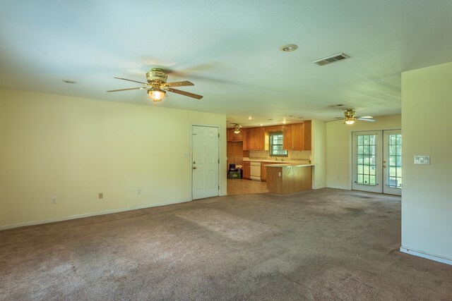 unfurnished living room featuring french doors, light colored carpet, and ceiling fan